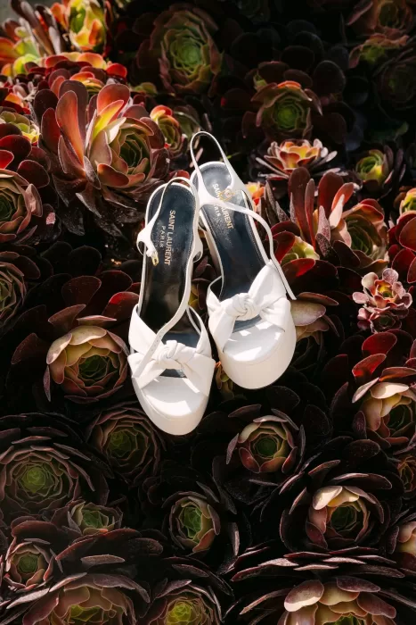 White Saint Laurent bridal heels resting on a bed of deep red succulents at Dimora Delle Balze.