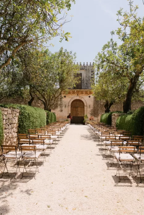Romantic outdoor ceremony setup lined with wooden chairs beneath olive trees at Dimora Delle Balze.