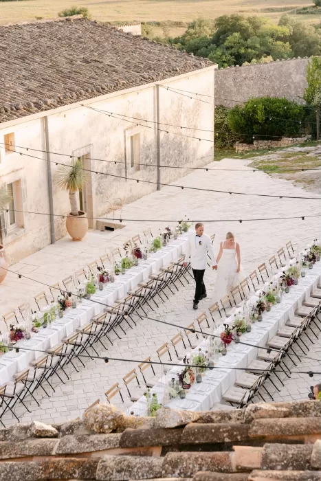 Long banquet tables elegantly decorated with florals and candles set in the courtyard of Dimora Delle Balze.
