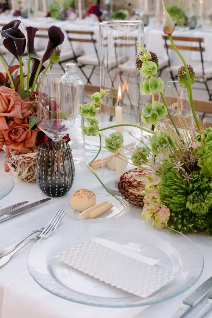 Close-up of wedding table decor with green florals, candles, and bread rolls elegantly arranged at Dimora Delle Balze.