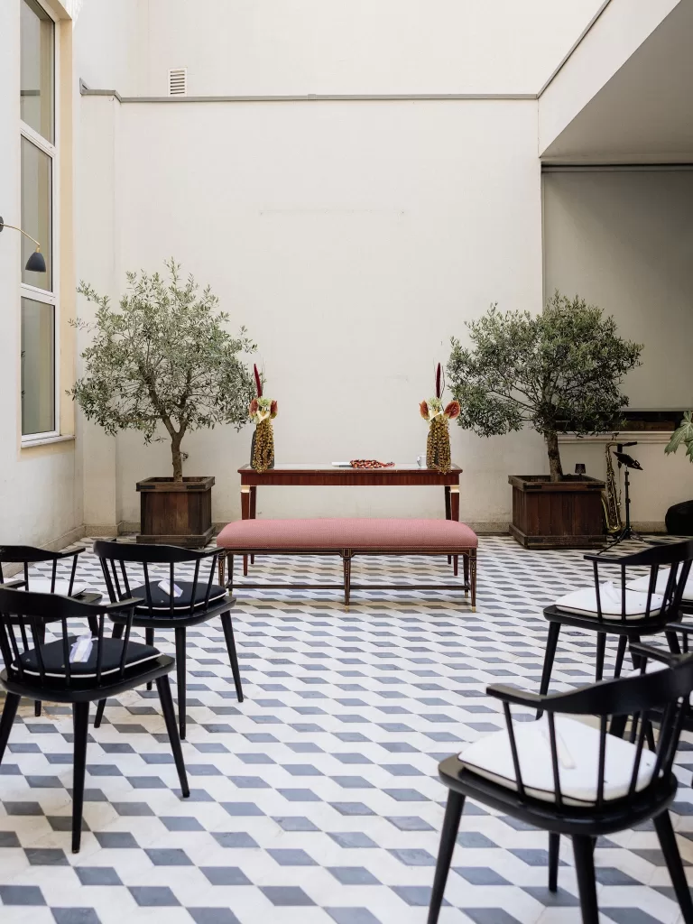 Wedding ceremony setup in the Infante Sagres courtyard with black chairs, olive trees, and floral arrangements.
