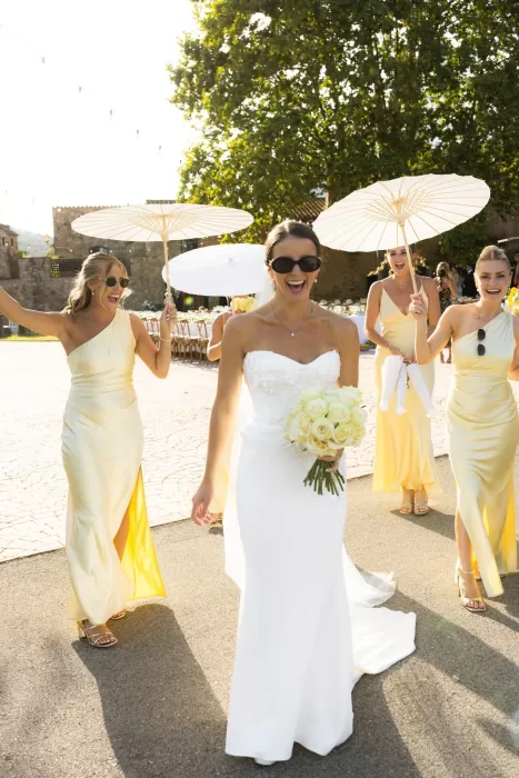 Bride and bridesmaids walking with parasols in the sunshine at Mas del Sord.