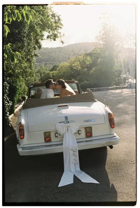 Couple sharing a kiss in the back of a vintage Rolls-Royce with a “Just Married” ribbon at Mas del Sord.