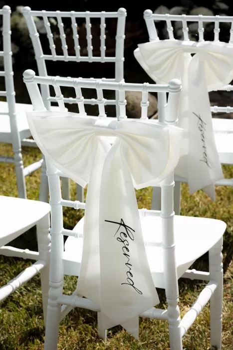 White ceremony chairs decorated with elegant reserved ribbons at Mas del Sord.
