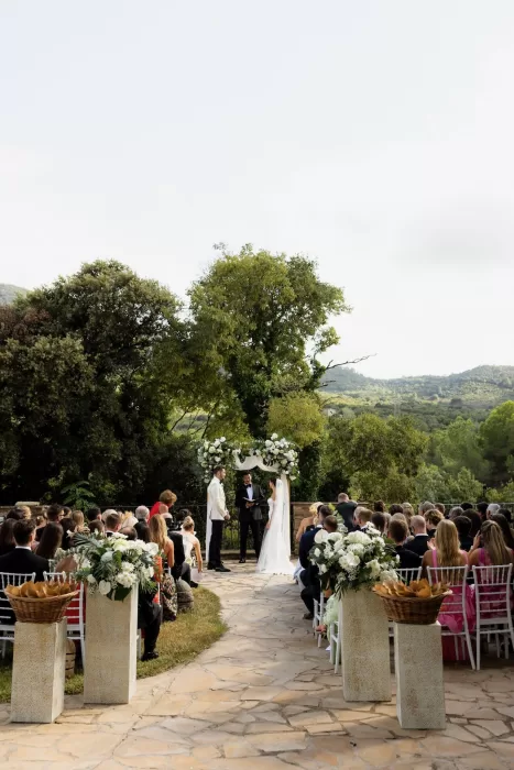 Outdoor ceremony at Mas del Sord with the couple standing beneath a floral arch surrounded by guests and mountain views.