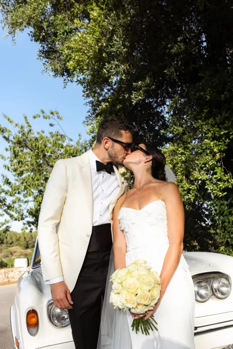 Bride and groom sharing a kiss beside a classic white car at Mas del Sord.