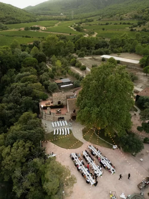 Aerial view of Mas del Sord showing long banquet tables under string lights surrounded by vineyards and greenery.