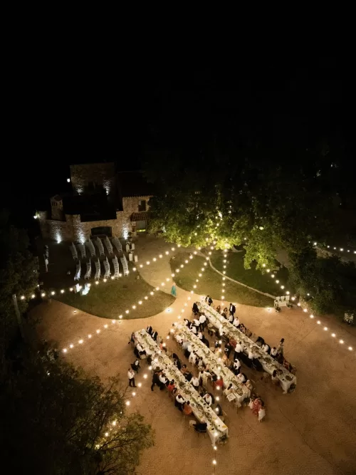 Nighttime aerial view of the candlelit outdoor dinner at Mas del Sord beneath glowing string lights.