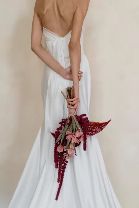 Minimalist back view of bride holding modern red and blush bouquet with trailing amaranthus at Villa Buttafava.
