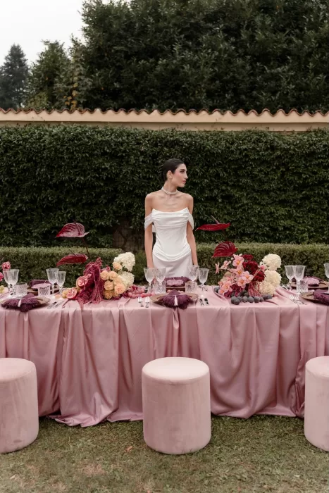 Elegant bride in white gown standing at a pink-toned outdoor wedding table at Villa Buttafava.