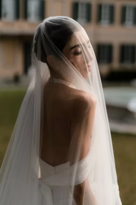 Elegant back view of bride in off-shoulder gown with flowing veil at Villa Buttafava.