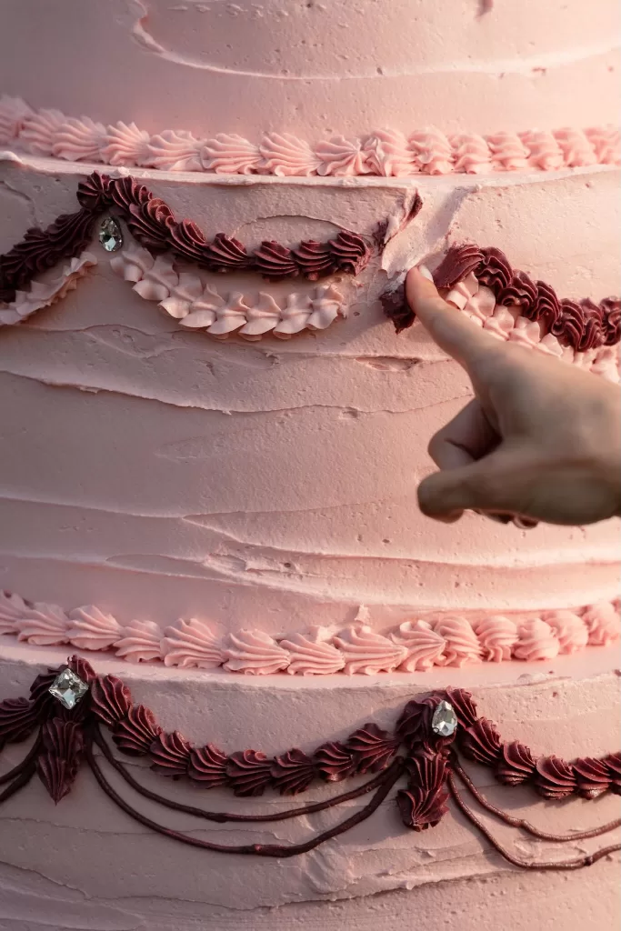 Close-up of intricate pink wedding cake frosting with burgundy piping details at Villa Buttafava.
