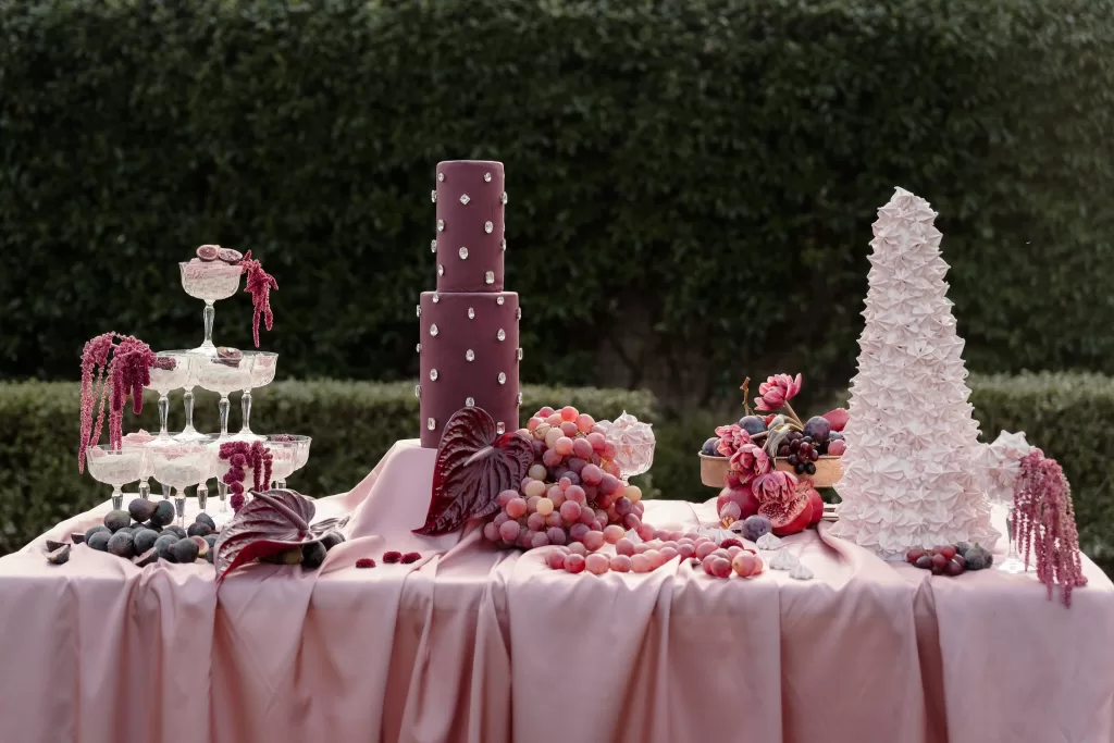 Artistic dessert display with sculptural cakes, grapes, and figs styled in rich pink hues at Villa Buttafava.
