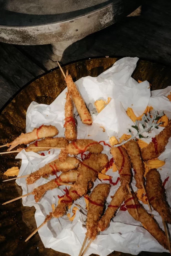 Fried wedding snacks served on parchment paper during the reception at Areias do Seixo, styled with rustic details.