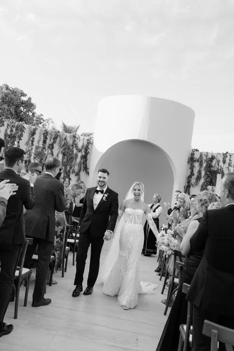 Newlyweds walking back down the aisle at Baja Luna as guests applaud following the ceremony.