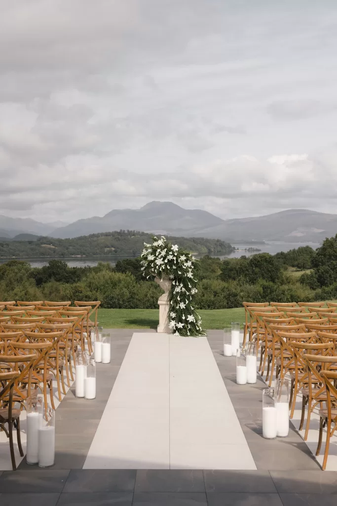 Outdoor wedding ceremony setup at Boturich Castle overlooking Loch Lomond and the surrounding hills.