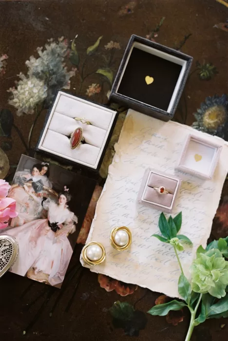 Elegant wedding details including rings, earrings, and handwritten letters styled on a floral table, reflecting Château du Prieuré’s romantic aesthetic.