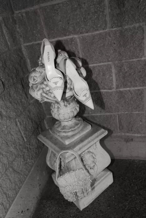 Bridal Prada heels and beaded handbag styled on a stone pedestal at Chateau Lill, captured in an editorial black-and-white detail shot.