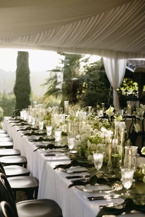 Refined wedding table details with green linens, white florals and glass candle holders under a marquee at Chateau Lill.