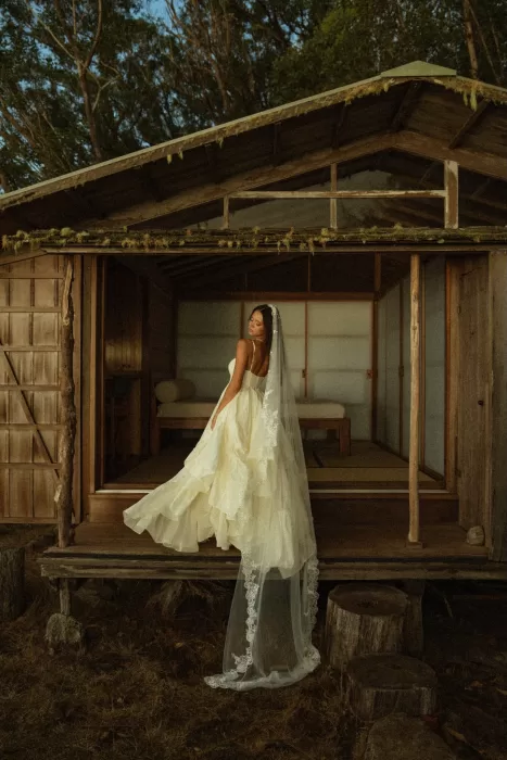 Bride standing on the porch of Ossipoff’s Cabin, showing the flowing silhouette of her dress and veil against the wooden cabin.