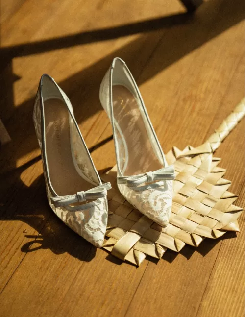 Lace wedding shoes resting on a woven mat inside Ossipoff’s Cabin, styled in soft afternoon light.