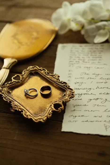 Wedding rings resting on a vintage tray beside handwritten vows, styled in a warm, editorial setting at Ossipoff’s Cabin.