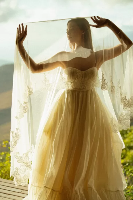 Bride lifting her veil in golden light with mountain views at Ossipoff’s Cabin, creating a soft, romantic silhouette.