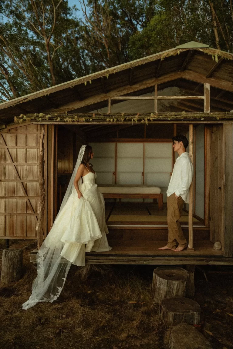 Bride and groom facing each other on the rustic wooden porch of Ossipoff’s Cabin, blending nature and minimalist design.