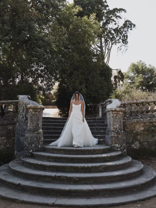 Bride descending historic stone steps in a minimalist gown at Vandelli Botanical Garden.