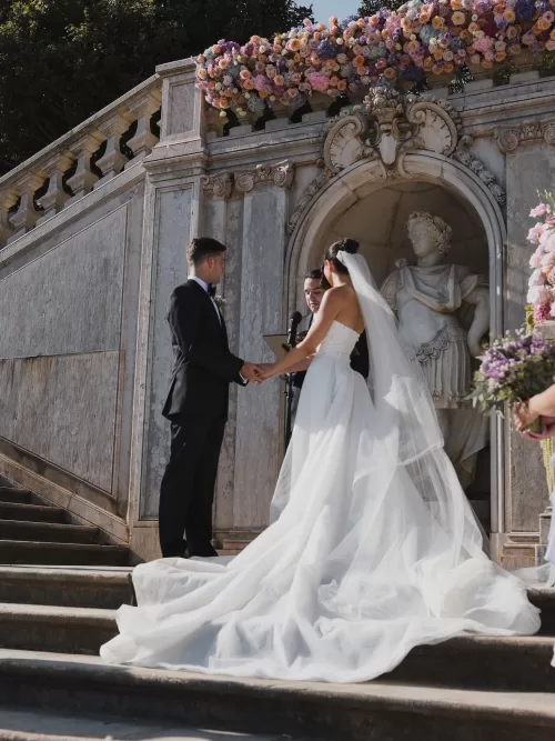 Outdoor wedding ceremony framed by florals and classical stone architecture at Vandelli Botanical Garden.