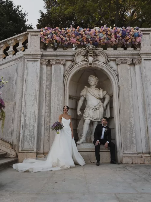 Ornate stone ceremony backdrop crowned with pastel florals at Vandelli Botanical Garden.