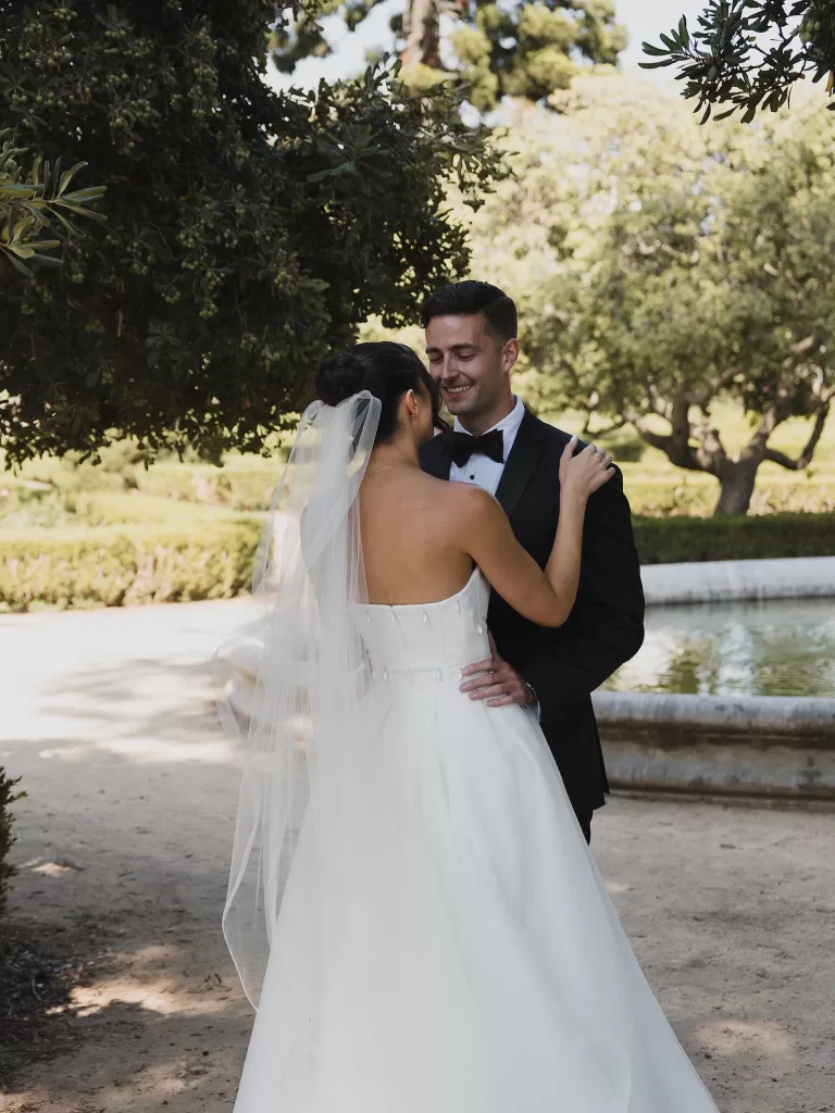 Bride and groom embracing beside a garden fountain at Vandelli Botanical Garden.