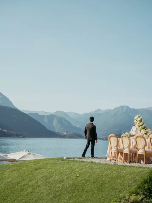 Groom standing by the lake during an elegant wedding at Villa Lario Resort