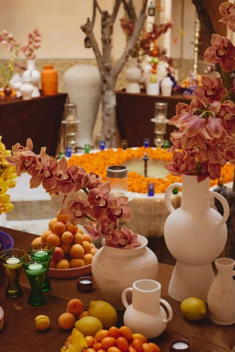 Elegant wedding centrepieces at Amanjena combining sculptural vases, orchids, citrus fruit and soft candlelight in the courtyard.