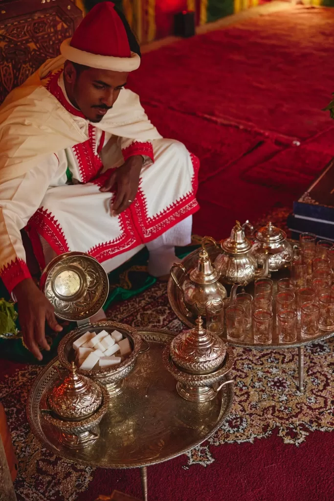 Traditional Moroccan tea service at an Amanjena wedding with silver teapots, glassware and rich red textiles.