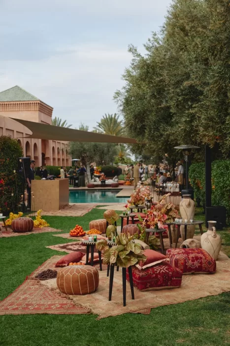 Poolside wedding lounge at Amanjena with relaxed seating, floral accents and Moroccan décor set among gardens and arches.