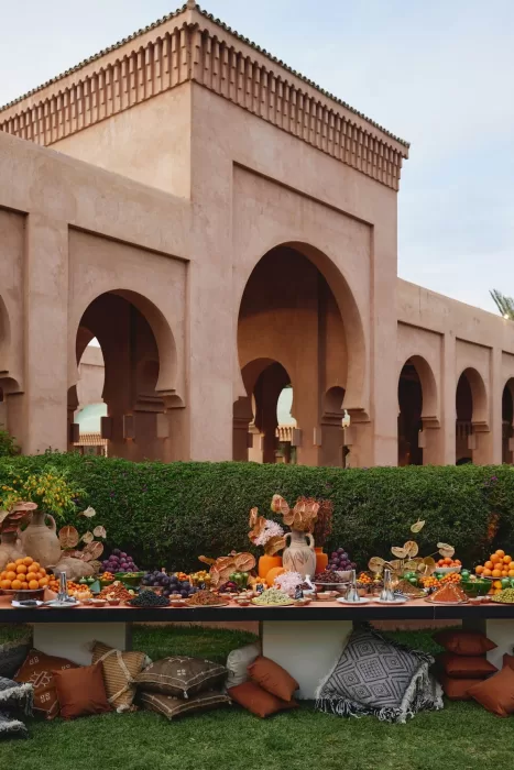 Moroccan wedding feast at Amanjena set beneath grand arches with abundant fruit displays, ceramics and relaxed garden seating.