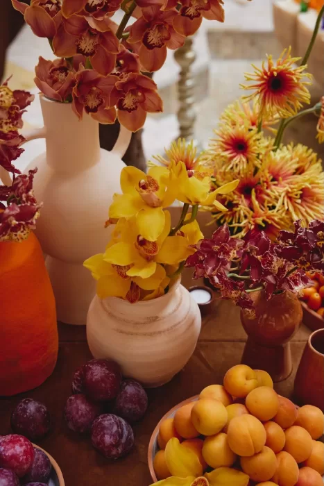 Close-up of floral wedding details at Amanjena featuring orchids, textured ceramics and seasonal fruit in warm sunset tones.