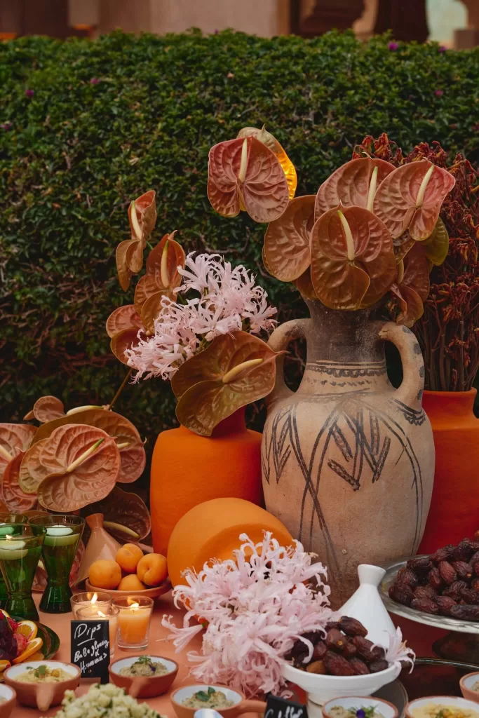 Close-up wedding table details at Amanjena with Moroccan ceramics, florals, candles and seasonal fruit.