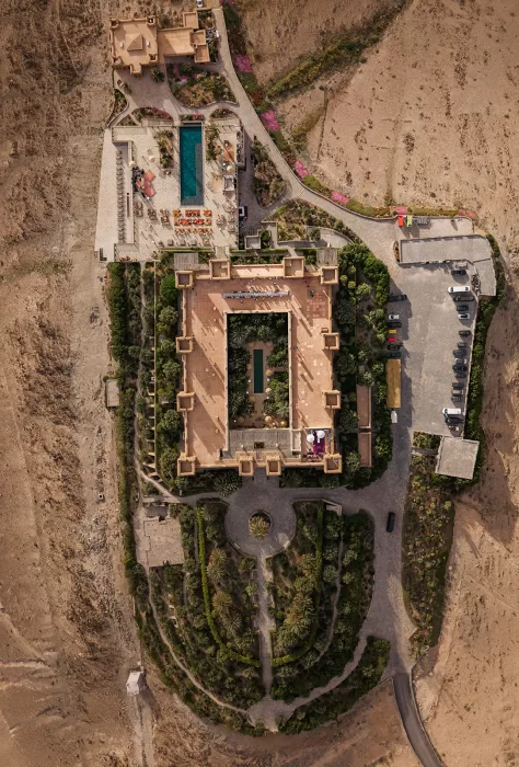 Exterior view of Amanjena set around the reflecting pool with Moroccan towers, arches and sunset light.
