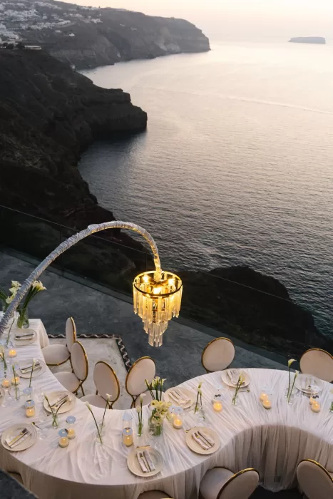 Elegant wedding reception tables arranged along the cliffs at Cavo Ventus, overlooking the sea at sunset with soft candlelight and sculptural lighting.