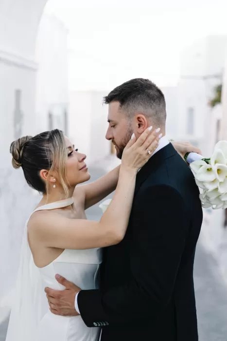 Intimate portrait of the bride and groom embracing in a whitewashed Santorini setting near Cavo Ventus.