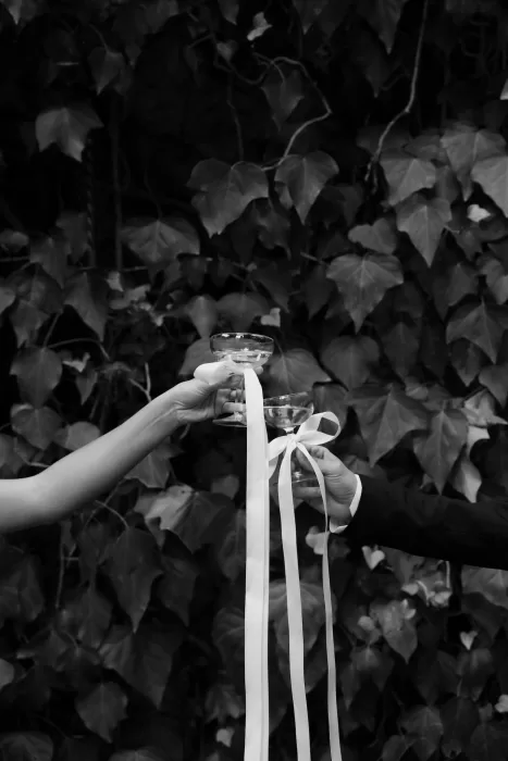 Wedding toast with coupe glasses tied in ribbon, set against ivy-covered walls at Finca Es Convent.