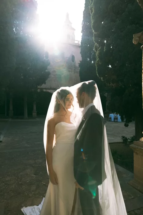 Couple standing beneath the bride’s veil at sunset in the courtyard of Finca Es Convent.