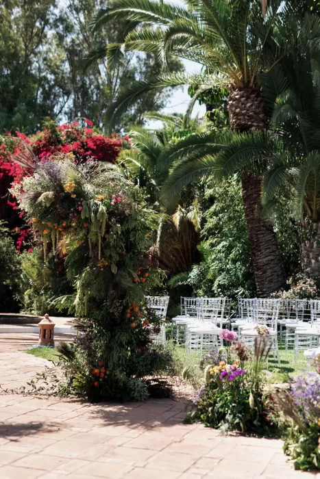 Floral ceremony arch surrounded by palm trees and garden paths at Finca La Concepción, set for an outdoor wedding.