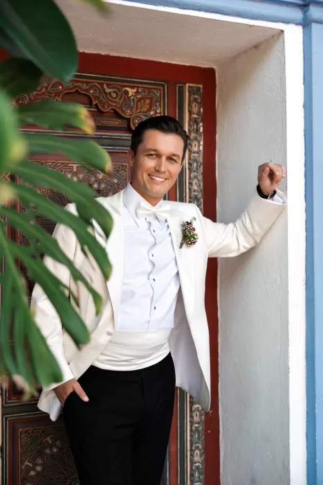 Groom in a white tuxedo posing against colourful tiled walls at Finca La Concepción, relaxed and confident before the ceremony.