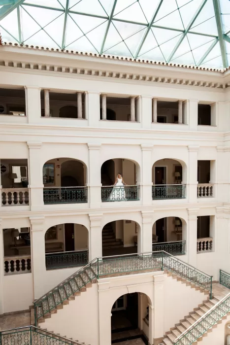 Bride standing on a balcony inside Finca La Concepción, surrounded by elegant arches and soft natural light.