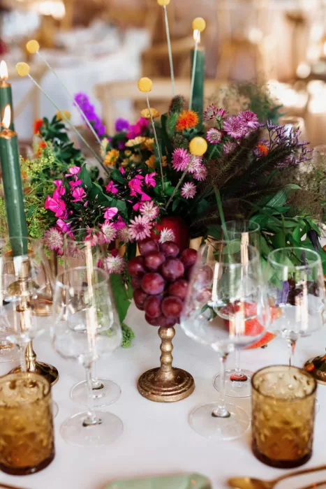 Colourful floral centrepiece with candles and fruit details on a wedding reception table at Finca La Concepción.