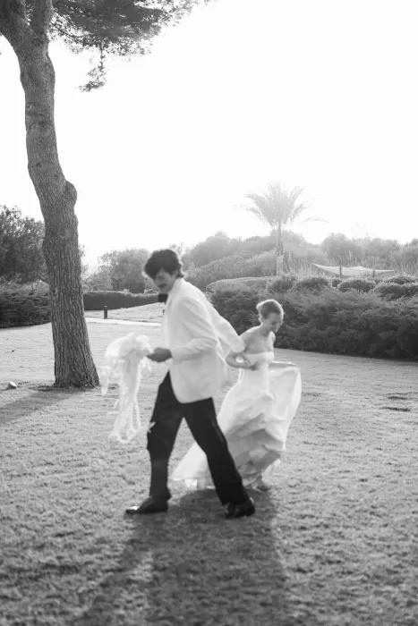 Black and white moment of the bride and groom running through the gardens at Fontsanta, capturing movement and joy.