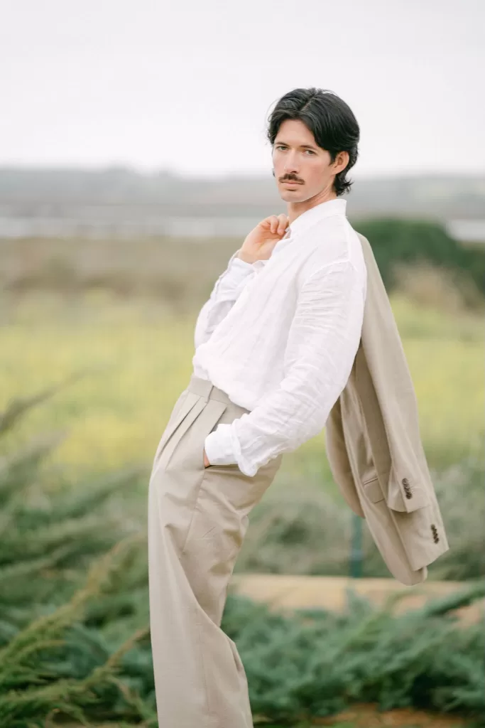 Fashion-forward groom portrait at Fontsanta wearing a relaxed linen shirt and tailored trousers in the countryside.
